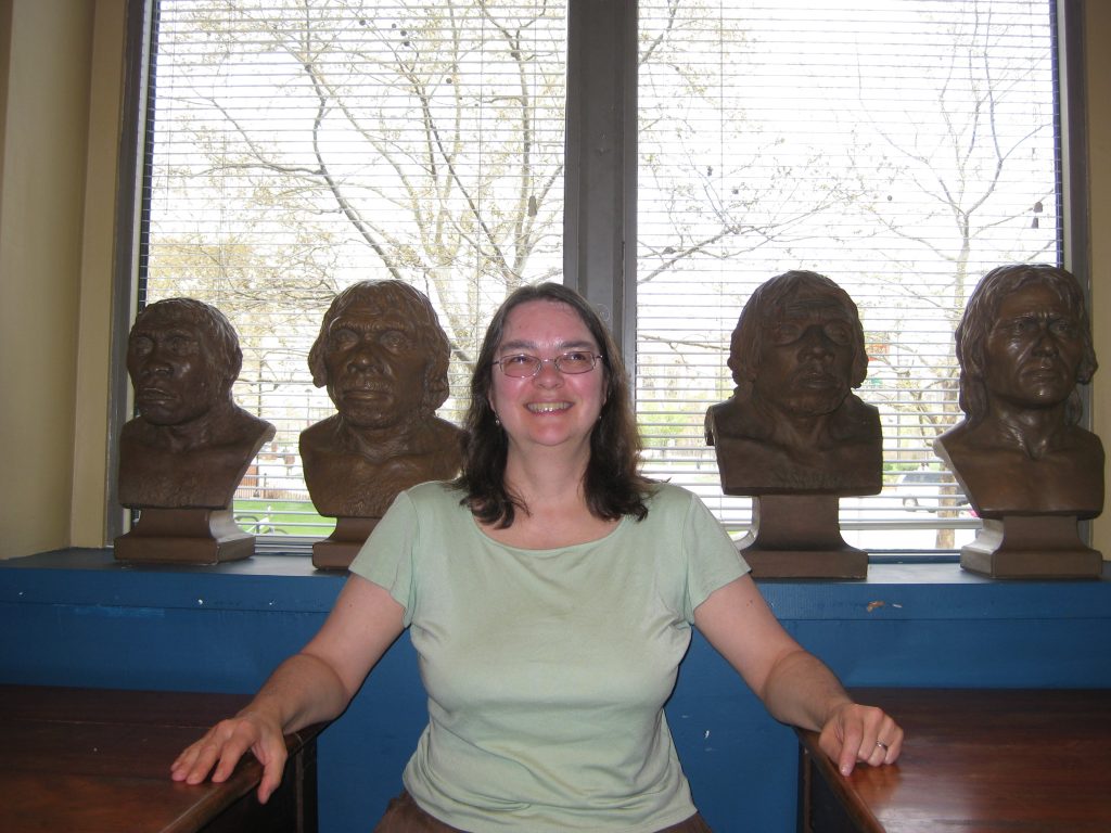 Connie Rinaldo poses with four busts at the Academy of Natural Sciences