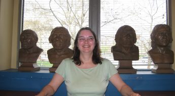 Connie Rinaldo poses with four busts at the Academy of Natural Sciences