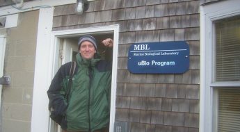 David Remsen smiles next to a sign for the Marine Biological Laboratory uBio Program