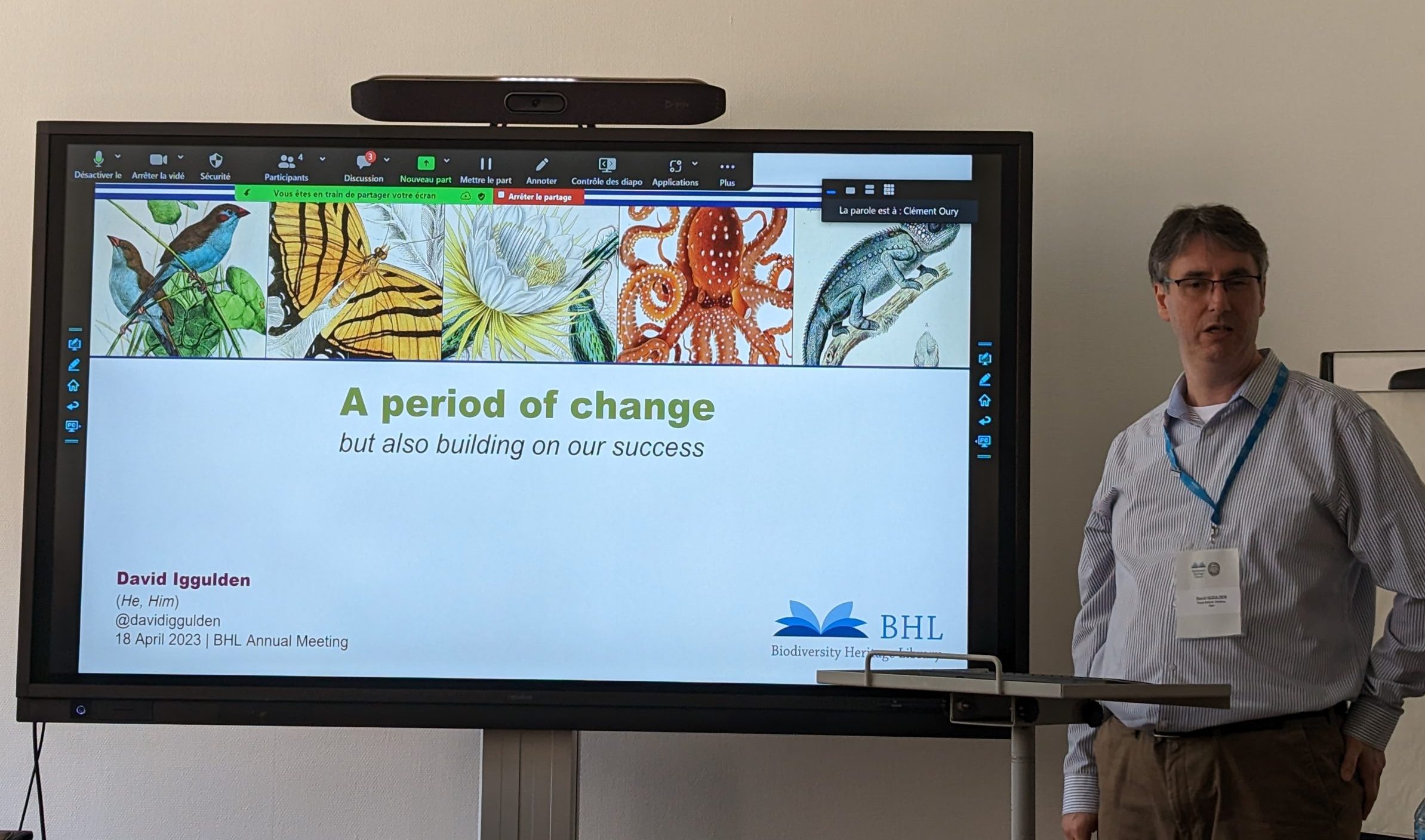 David Iggulden stands next to a large monitor to begin his talk at the BHL Annual Meeting