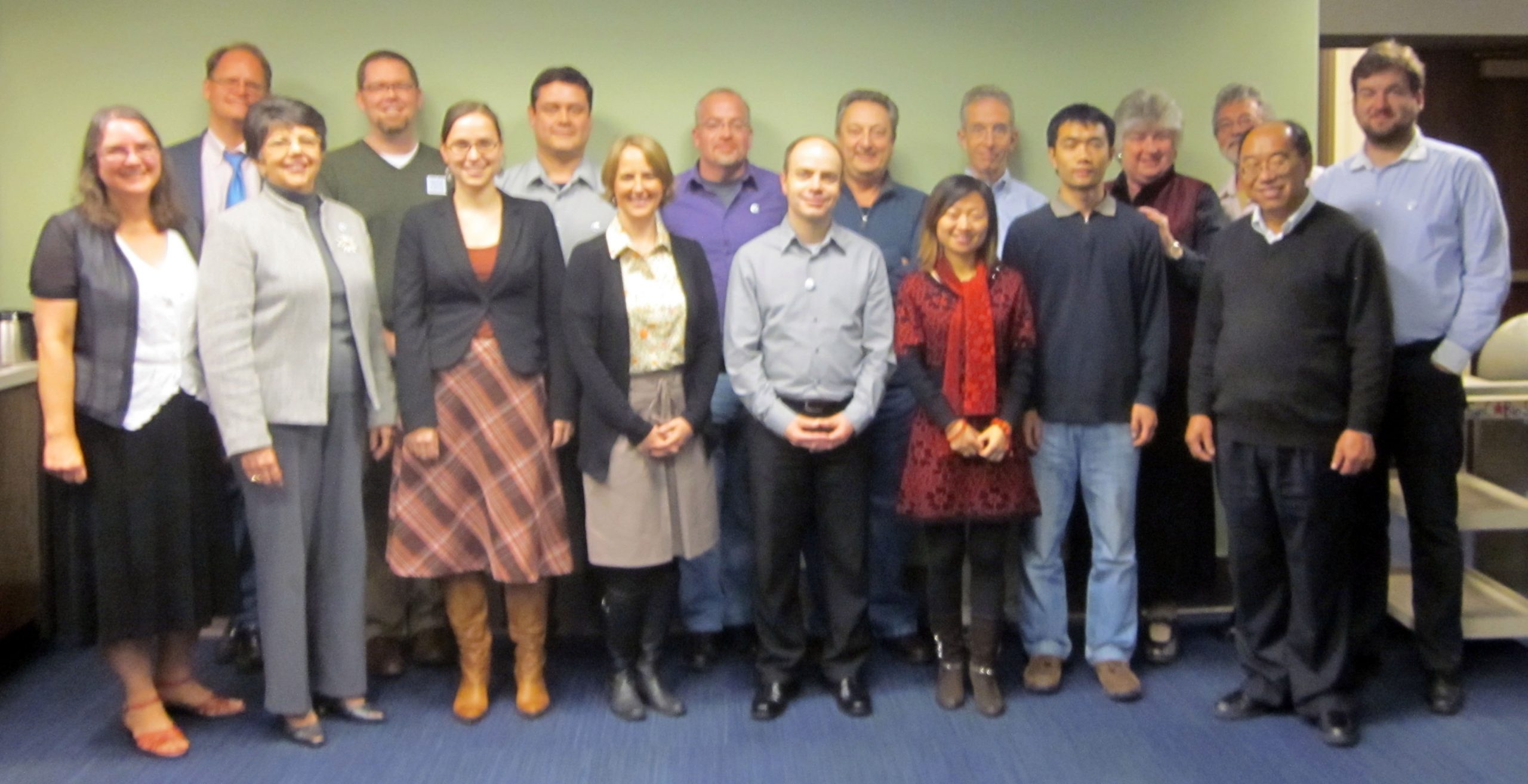 Global BHL meeting attendees stand in two rows for a group photo in a conference room