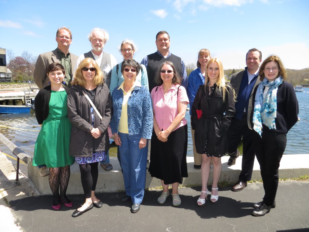 Nancy Gwinn stands with BHL meeting attendees for a group photo in front of the bay in Woods Hole, MA