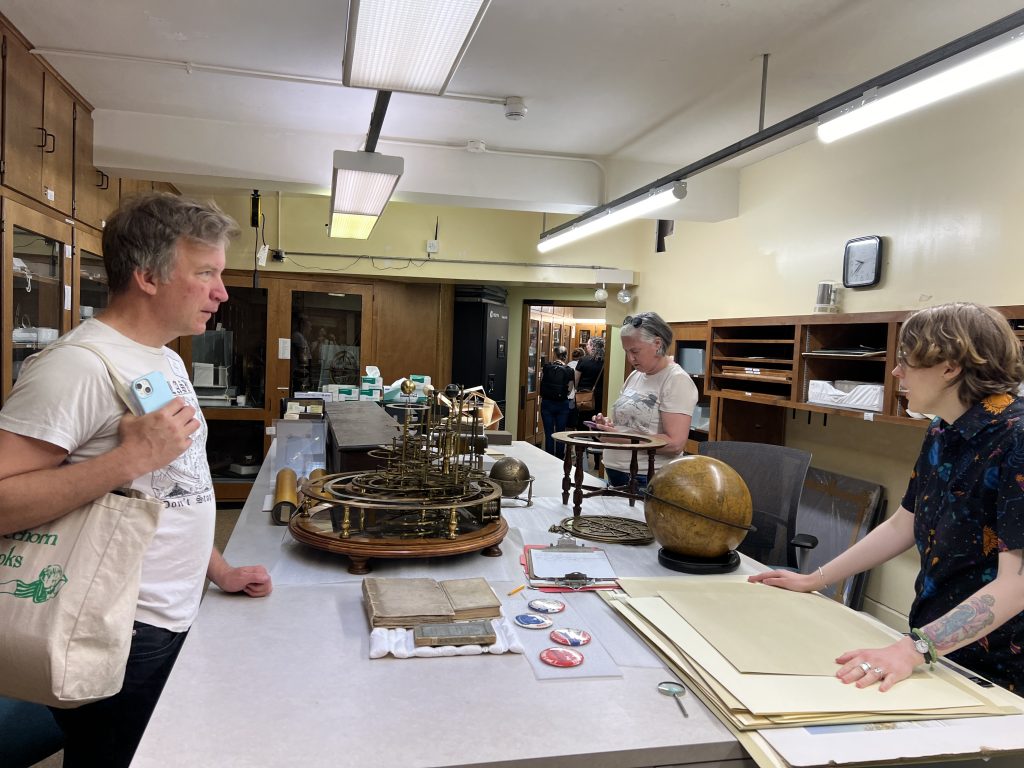 People explore cabinets and tables of astronomical equipment and books