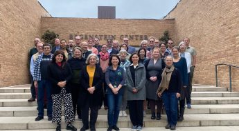 A group of people pose for a picture on the steps in front of the Regenstein Center