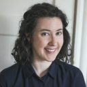 Woman with dark hair in a black shirt smiling at the camera