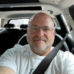 Profile of Matt Person with a beard and glasses in a car