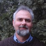 head shot photo of a man in a brown sweater