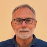 Man with glasses, grey beard, and dark shirt