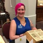 Photo of a woman in a blue top with pink hair.