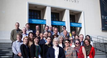 group of men and women standing in front of a white building labeled "Los Angeles County Museum of Natural History"