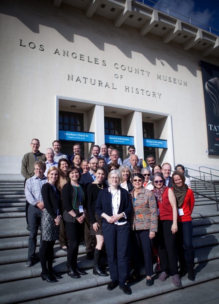 group of men and women standing in front of a white building labeled "Los Angeles County Museum of Natural History"