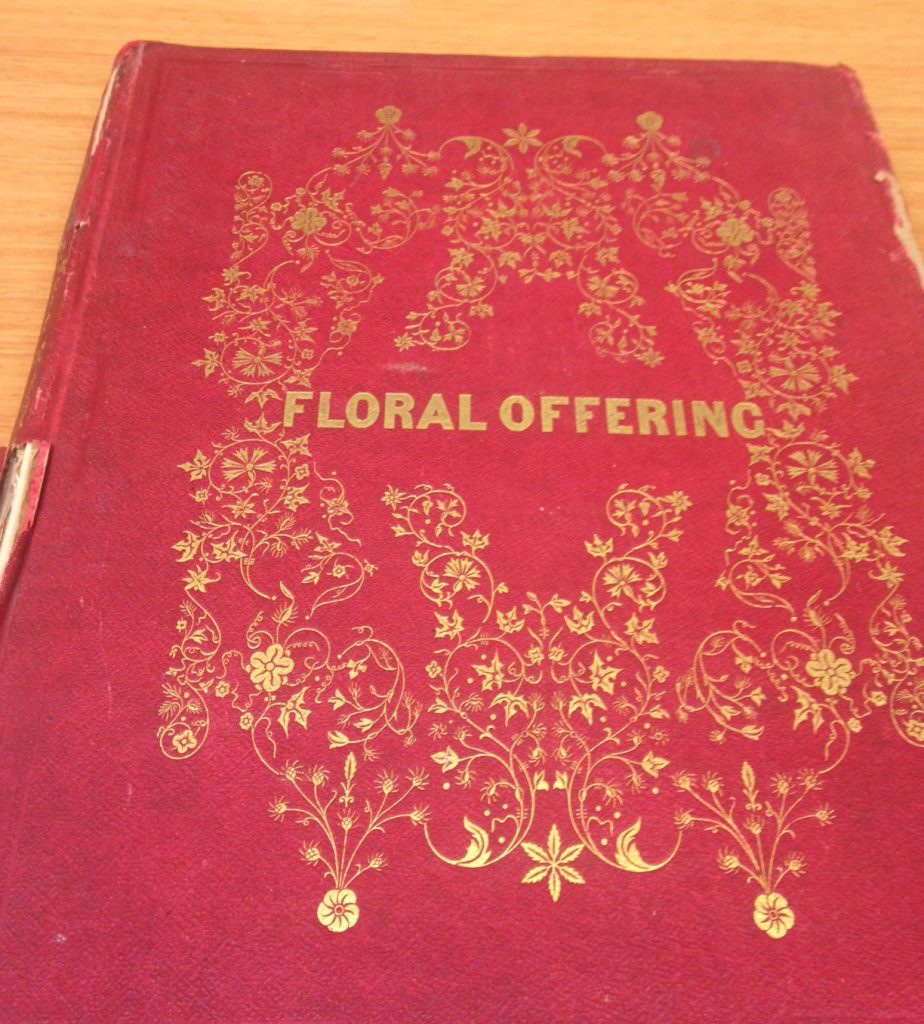 book with red binding and imprint of gold flowers