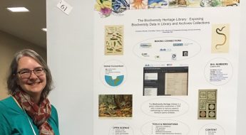 woman in green shirt standing in front of a poster.