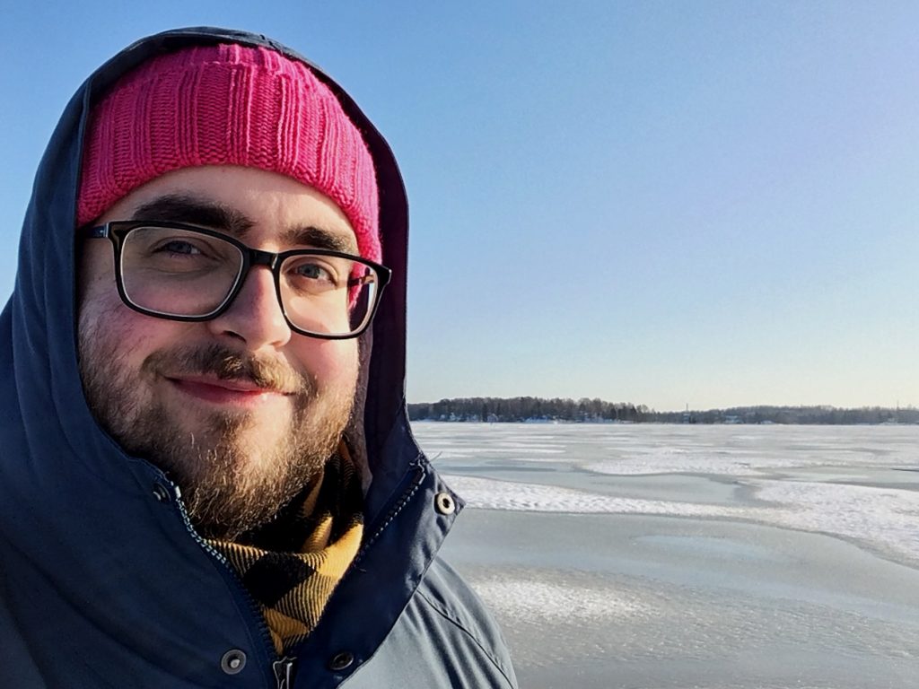 white male in red hate standing in a snowy landscape
