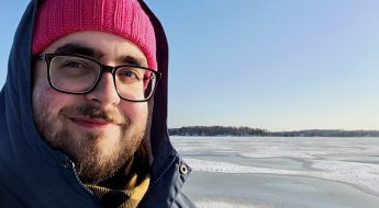 white male in red hate standing in a snowy landscape