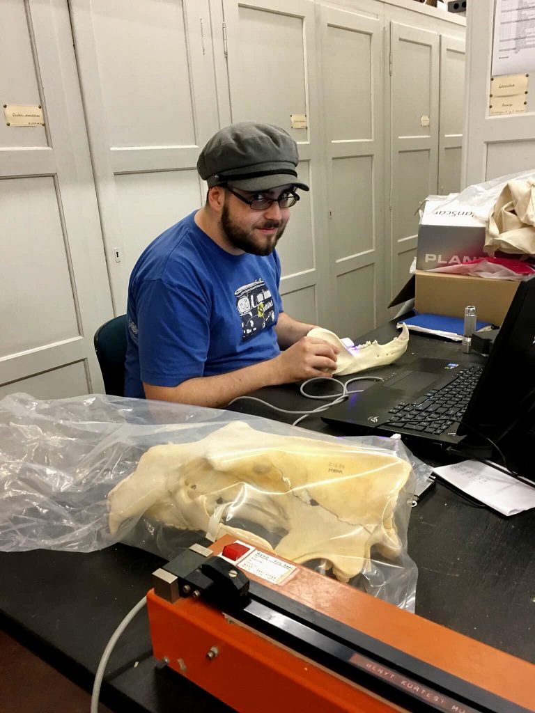 white male in a blue shirt analyzing an animal skill in a lab