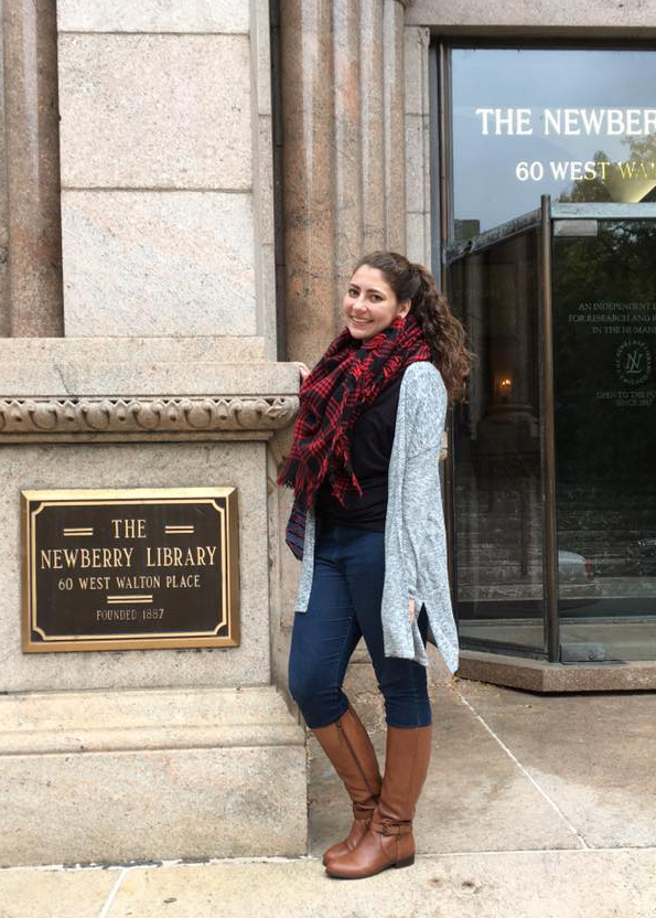 Photograph of a woman standing in front of a glass door.