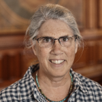 Photograph of a woman with gray hair and a checkered shirt.