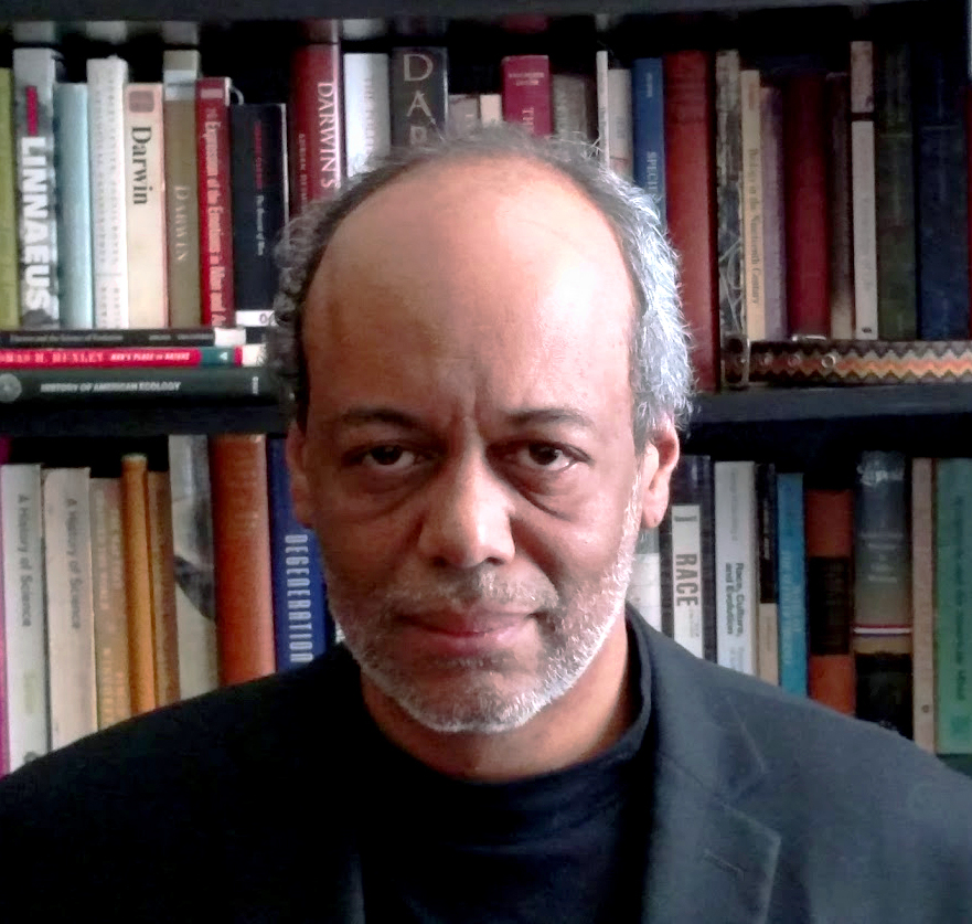 Photo of a man standing in front of a book case.
