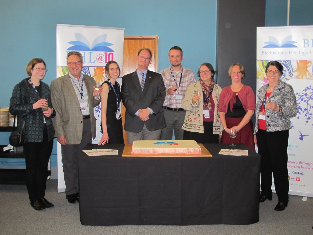 group of people standing around a BHL birthday cake
