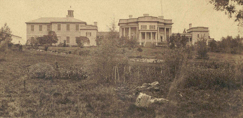 Black and white photo of victorian buildings in a garden