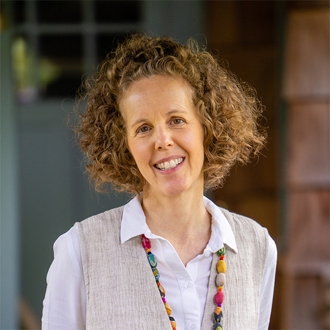 Photo of a person with curly brown hair smiling at the camera