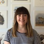 Head shot of a woman with shoulder length brown hair wearing and black and white striped shirt.