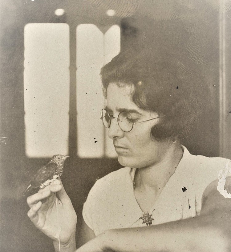 Black and white photo of a woman with short dark hair, wearing glasses, holding a bird.