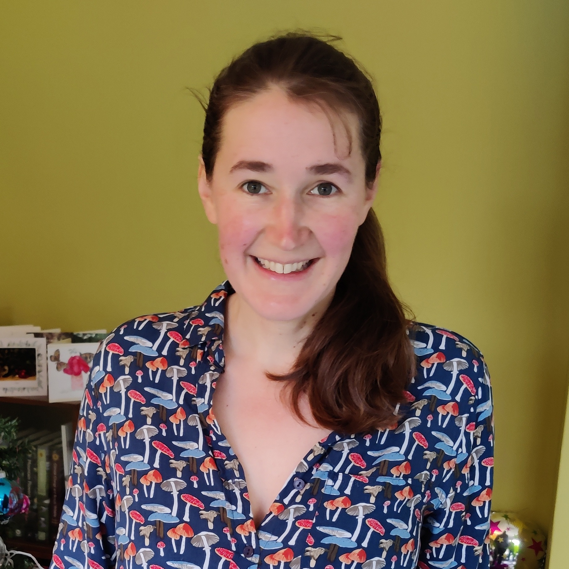 Photo of a human with long brown hair in a shirt with fungi images on it.
