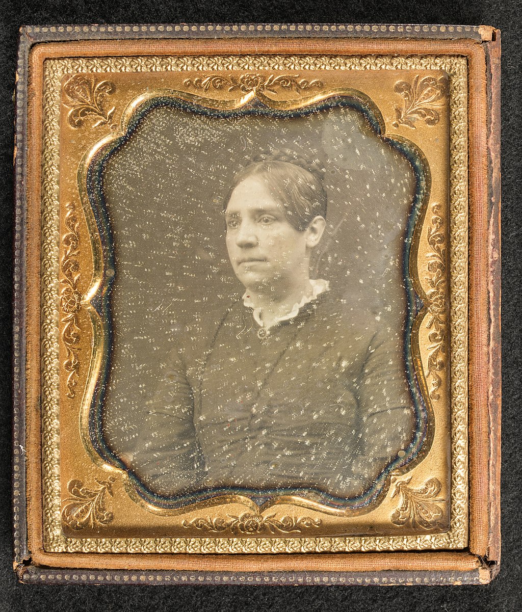 Black and white portrait of a woman in a gold frame.