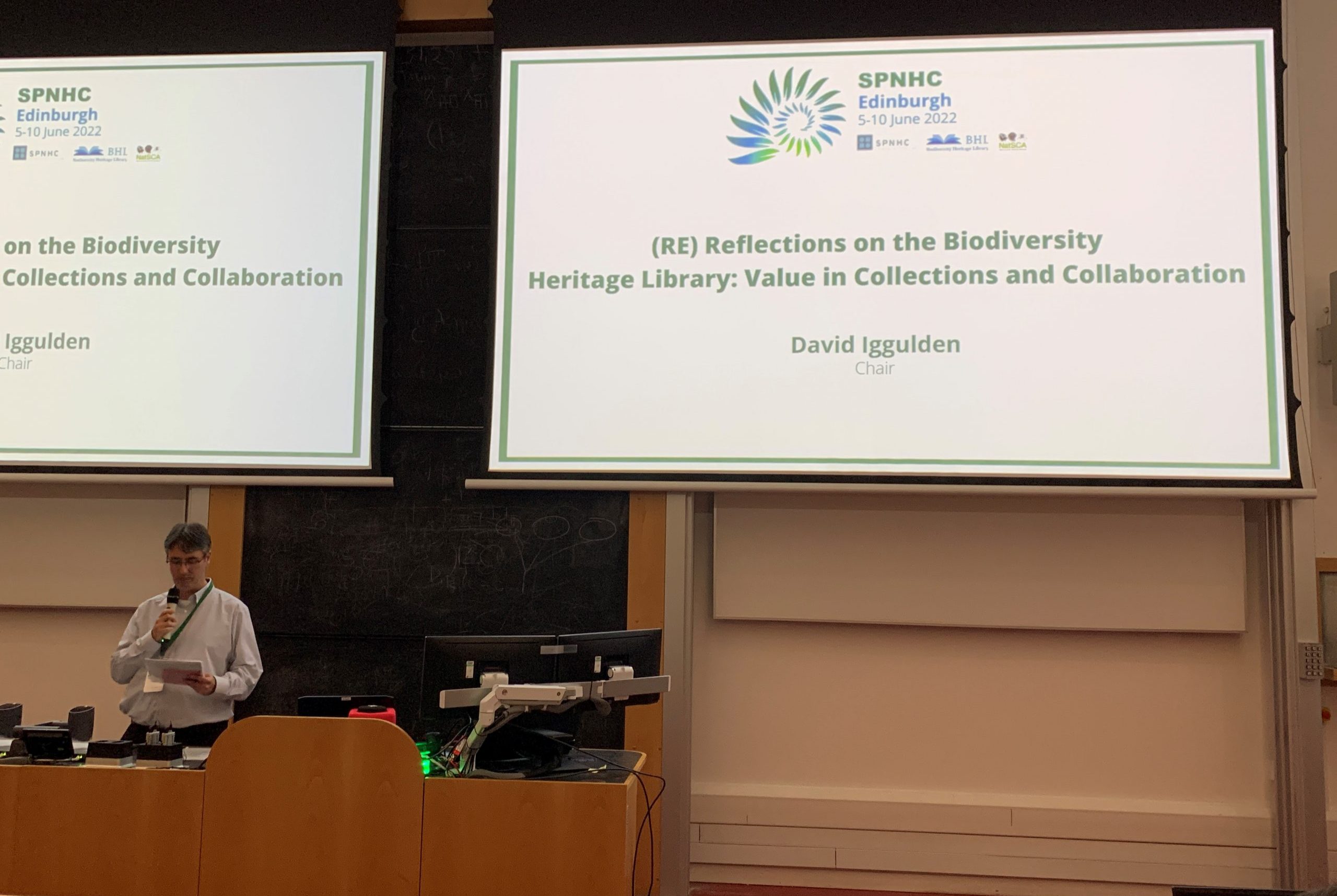 A speaker at a lectern presents to a lecture hall