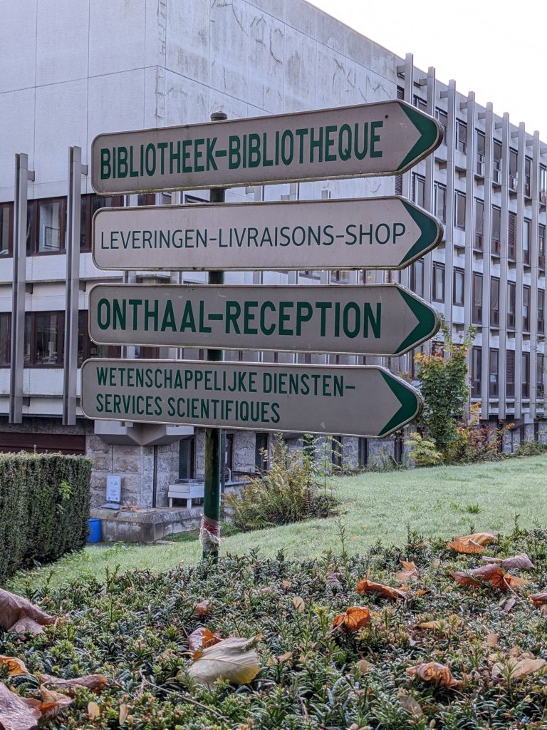 Directional signs pointing to the library, shop, reception, and scientific services