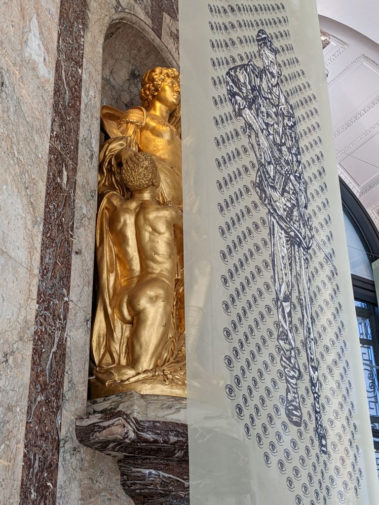 View from below, looking up at one of the 16 semi-transparent veils hung in front of a golden statue
