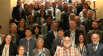 Group photo of meeting attendees assembled on the grand stair case of the Comics Art Museum