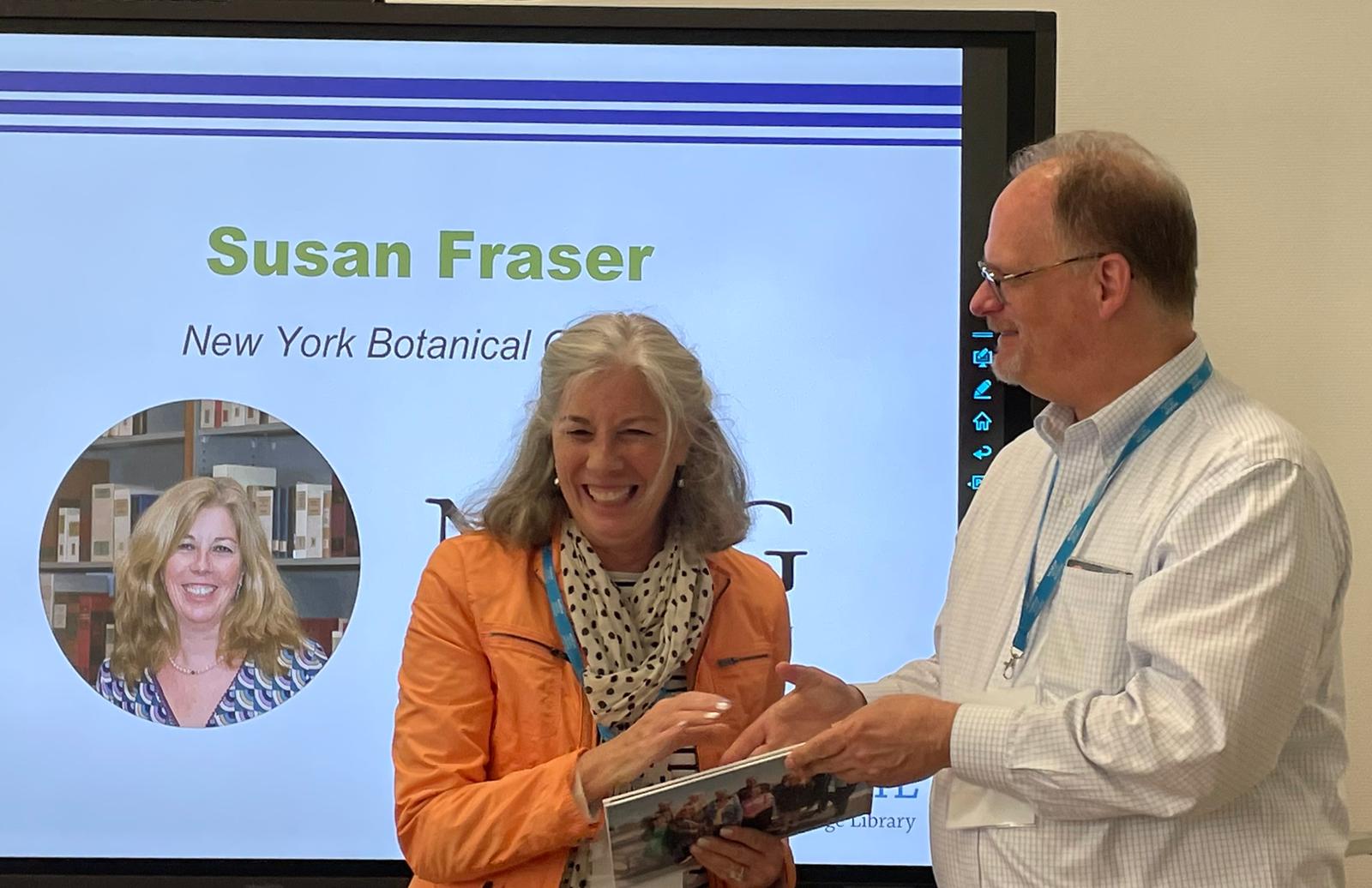 Susan Fraser smiles as she receives a photo album from Martin Kalfatovic