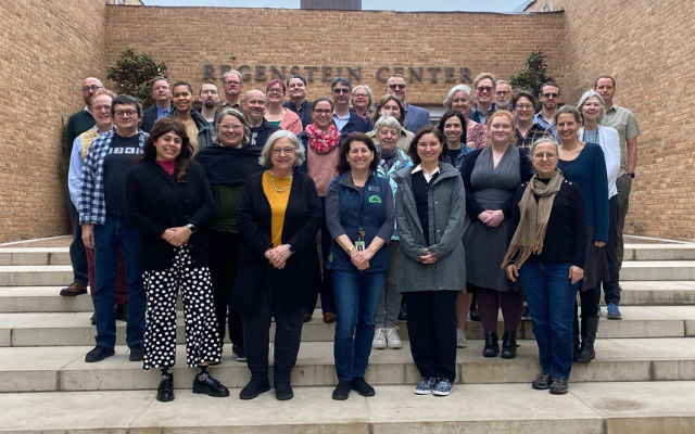 A group of people pose for a picture on the steps in front of the Regenstein Center