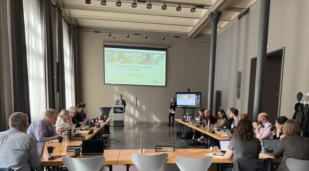 Man at podium presents "Towards a new chapter for BHL" to an audience seated at tables