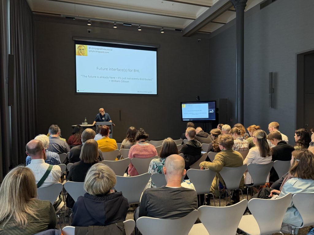 A person presents from a podium to a seated audience 