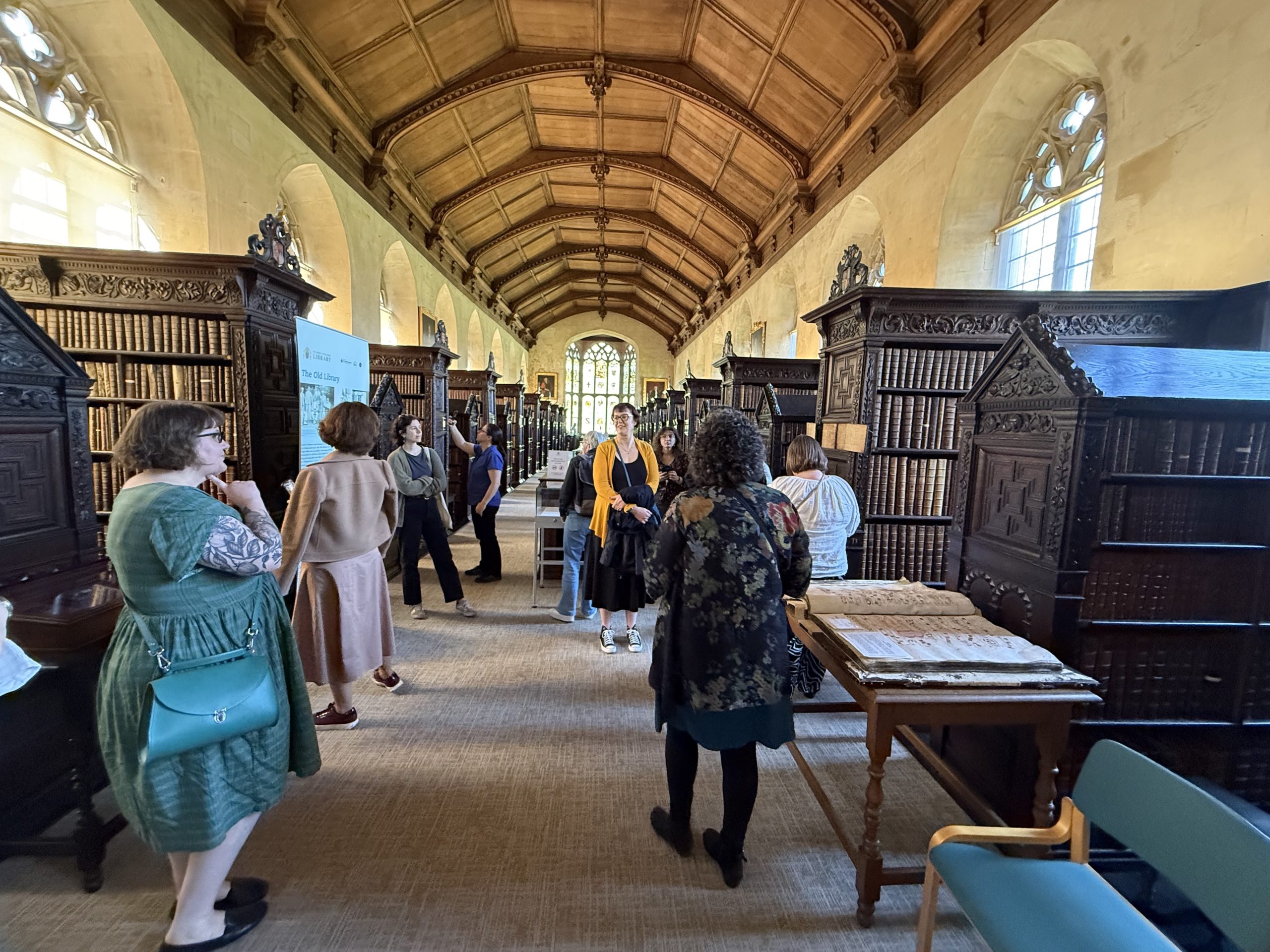 A group of people perusing books and bookshelves in an historic library.